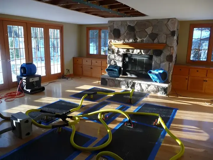 Drying mats and air movers on a hardwood floor during a Manchester dry-out
