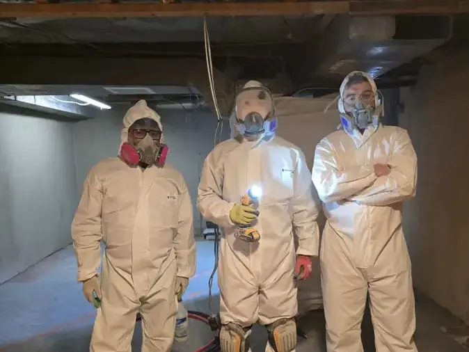 Restoration crew in full protective gear in a basement after a sewer backup