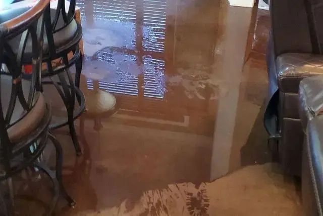 Standing water across a Manchester basement rec room after a sump pump failure